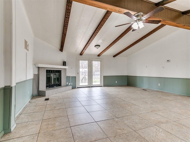 unfurnished living room featuring ceiling fan, a fireplace, light tile patterned flooring, and lofted ceiling with beams