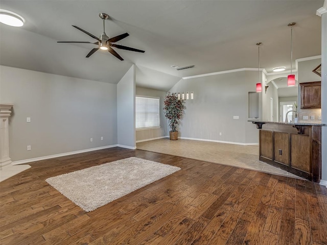 unfurnished living room with ceiling fan, dark hardwood / wood-style flooring, vaulted ceiling, and ornamental molding