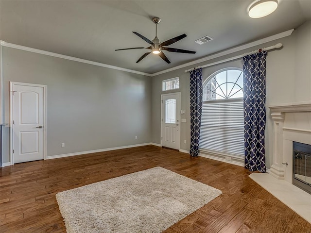 unfurnished living room featuring ceiling fan, ornamental molding, and dark wood-type flooring