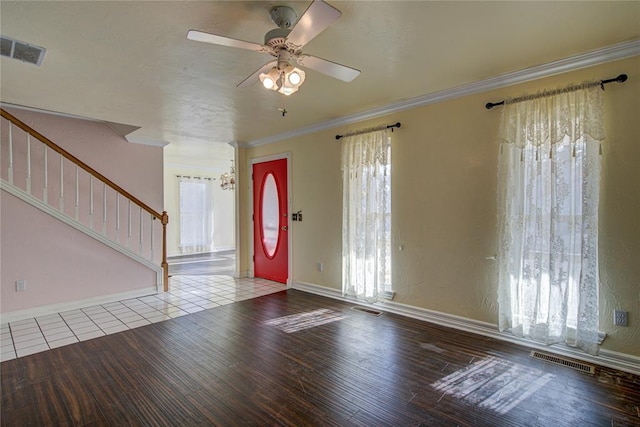 foyer entrance with wood-type flooring, ceiling fan with notable chandelier, plenty of natural light, and ornamental molding