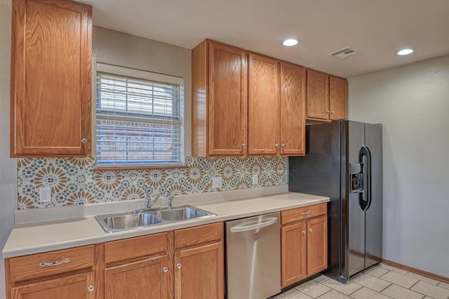 kitchen with tasteful backsplash, stainless steel dishwasher, black refrigerator with ice dispenser, sink, and light tile patterned floors