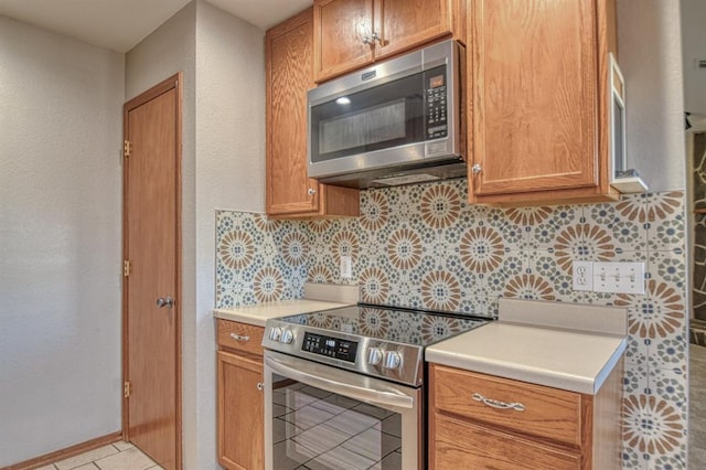 kitchen with decorative backsplash, light tile patterned floors, and stainless steel appliances