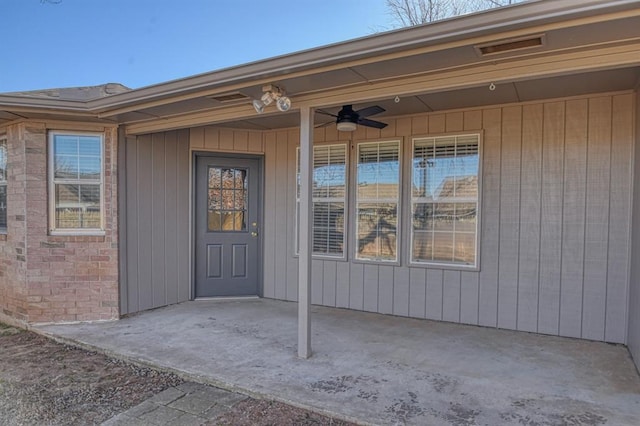 view of exterior entry featuring ceiling fan and a patio area