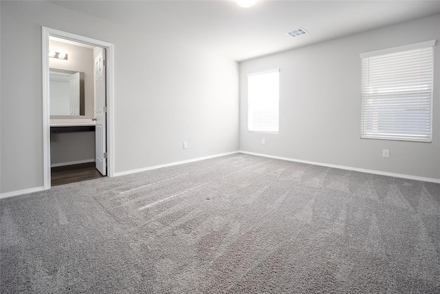 unfurnished bedroom with dark carpet and connected bathroom