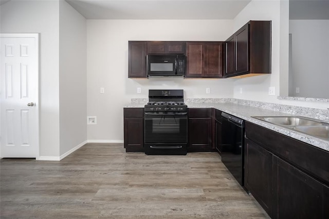 kitchen featuring black appliances, dark brown cabinets, sink, and light hardwood / wood-style flooring