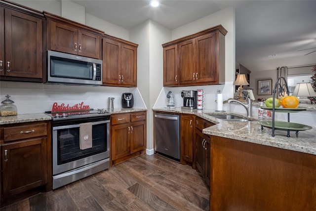 kitchen featuring backsplash, light stone counters, sink, and stainless steel appliances