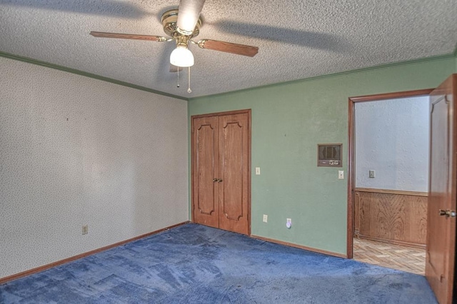 spare room featuring ceiling fan, wood walls, crown molding, and a textured ceiling