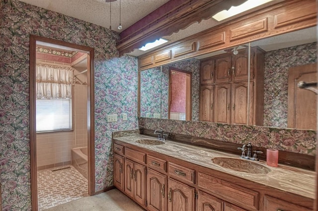 bathroom with a textured ceiling, vanity, and a bath