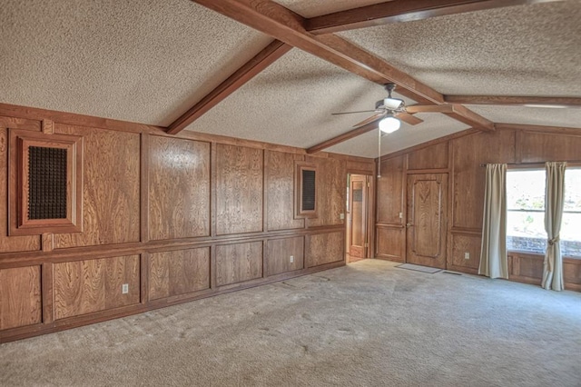 unfurnished living room with wooden walls, ceiling fan, light carpet, and a textured ceiling