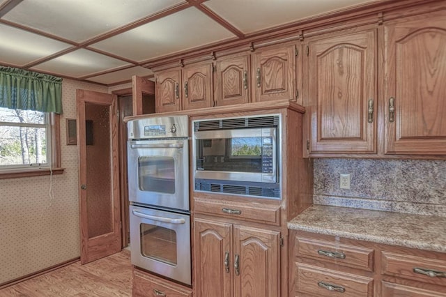 kitchen with stainless steel appliances, light hardwood / wood-style flooring, and tasteful backsplash