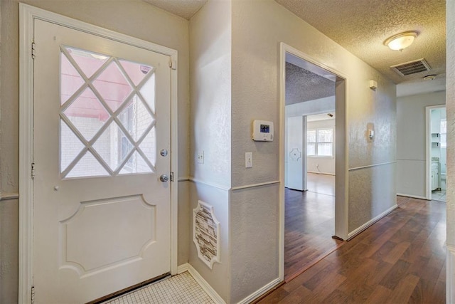 doorway with a textured ceiling and dark wood-type flooring