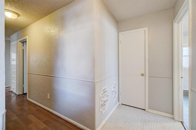 corridor with a textured ceiling and hardwood / wood-style flooring