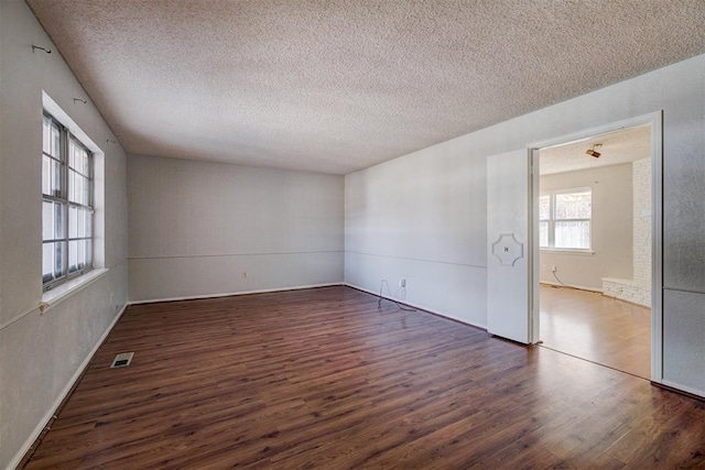 unfurnished room featuring a textured ceiling and dark hardwood / wood-style flooring