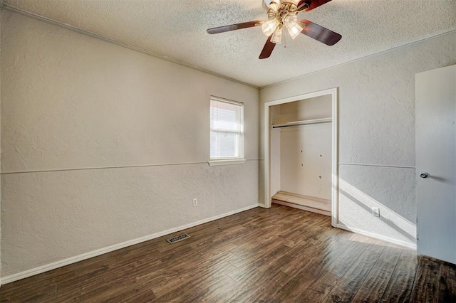 unfurnished bedroom with a closet, ceiling fan, dark hardwood / wood-style flooring, and a textured ceiling