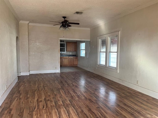 unfurnished living room with ceiling fan, dark hardwood / wood-style flooring, crown molding, and a textured ceiling