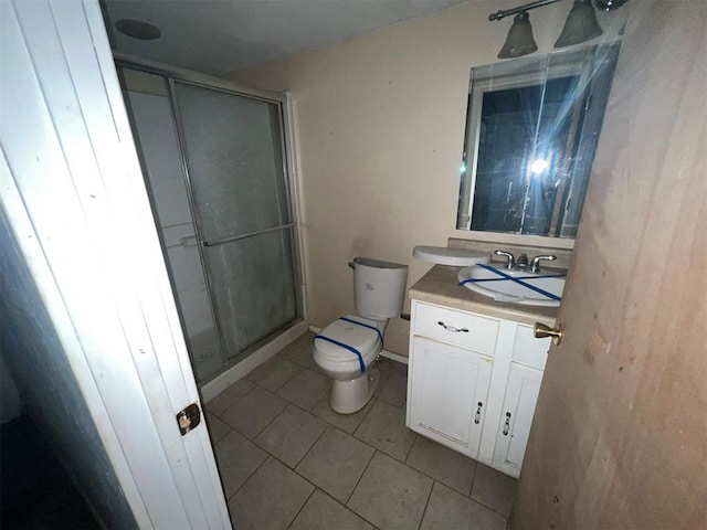 bathroom with tile patterned floors, toilet, vanity, and walk in shower