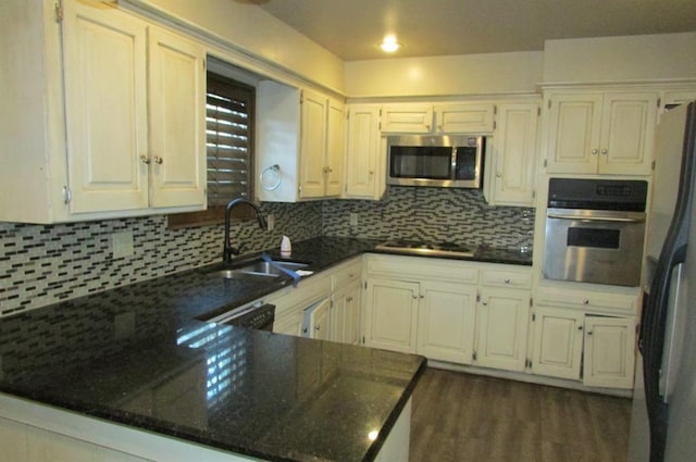 kitchen with sink, stainless steel appliances, tasteful backsplash, white cabinets, and kitchen peninsula