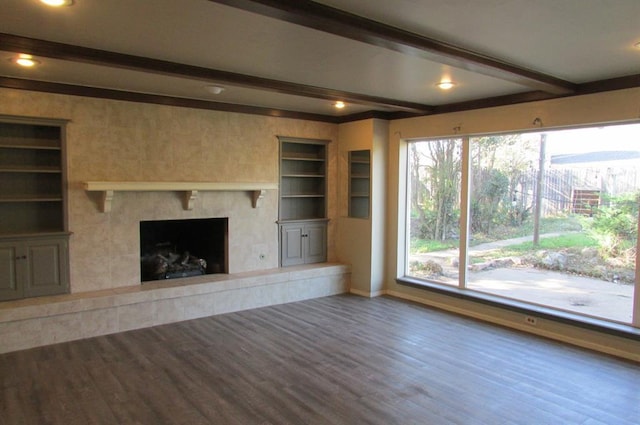 unfurnished living room featuring beamed ceiling, hardwood / wood-style floors, built in features, and a fireplace