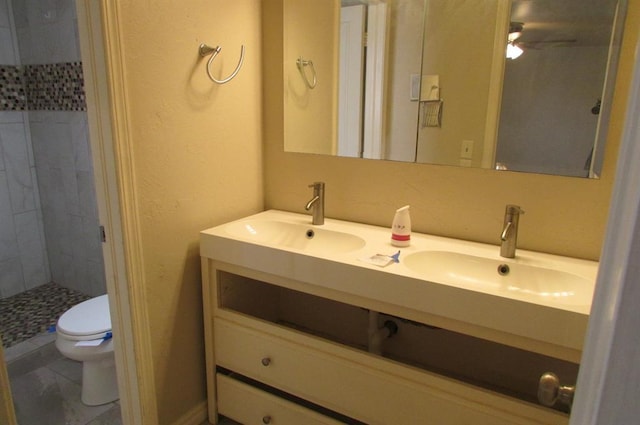 bathroom with vanity, tiled shower, and toilet