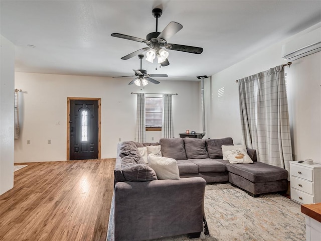 living room featuring light hardwood / wood-style flooring, ceiling fan, and a wall unit AC