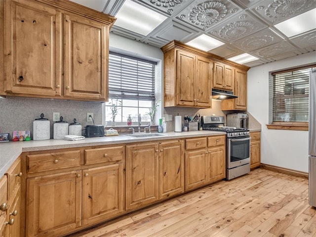 kitchen featuring backsplash, light hardwood / wood-style floors, sink, and gas range