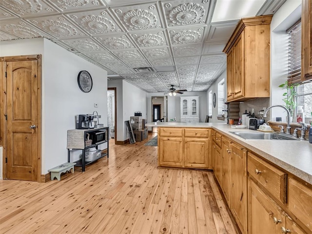 kitchen featuring kitchen peninsula, light hardwood / wood-style flooring, a healthy amount of sunlight, and sink