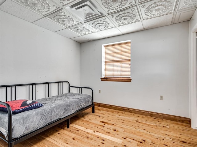 bedroom with hardwood / wood-style floors and a paneled ceiling