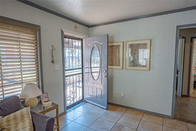 entryway with a textured ceiling, ornamental molding, and light tile patterned flooring