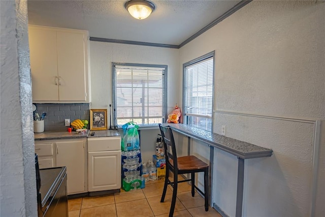 kitchen featuring backsplash, ornamental molding, electric range, white cabinetry, and light tile patterned flooring