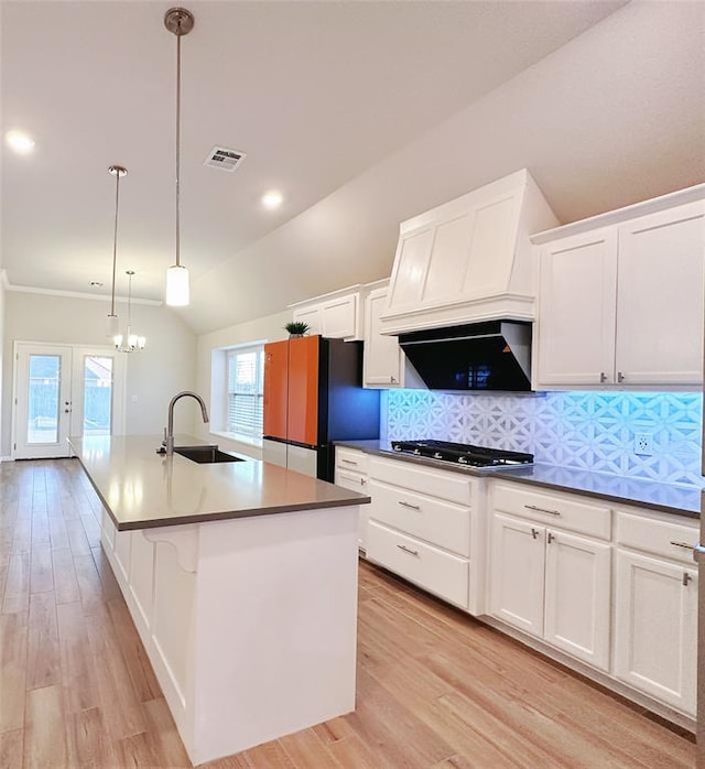 kitchen featuring stainless steel gas stovetop, lofted ceiling, a kitchen island with sink, black fridge, and sink