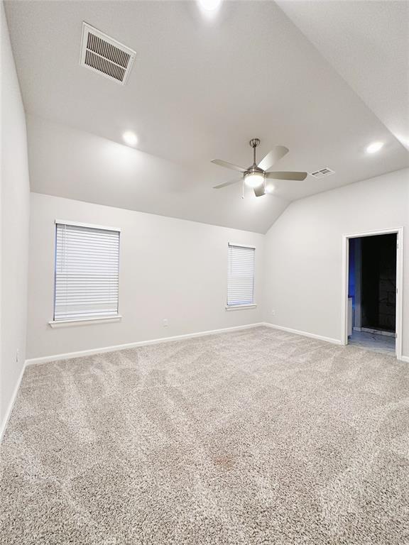 empty room with carpet floors, vaulted ceiling, and ceiling fan