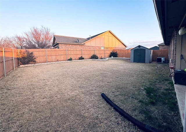 view of yard featuring a fenced backyard, central AC unit, a storage shed, and an outdoor structure