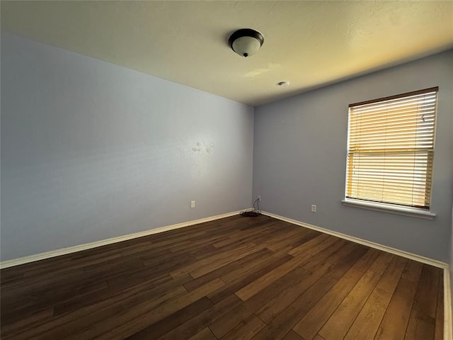 empty room featuring dark wood finished floors and baseboards