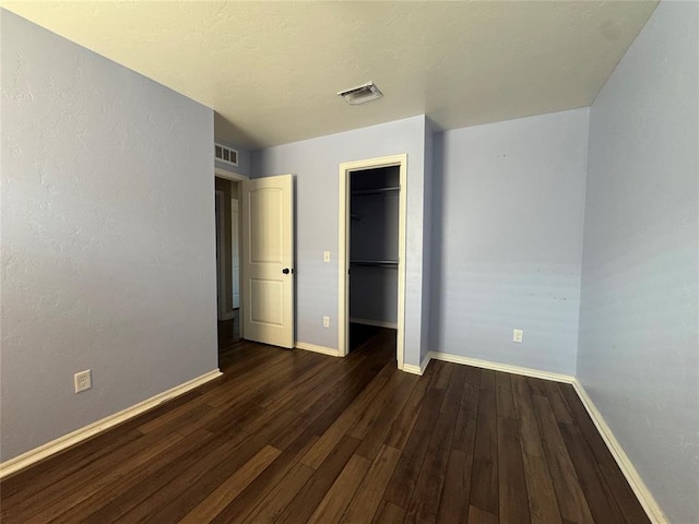 unfurnished bedroom with visible vents, baseboards, and dark wood-type flooring