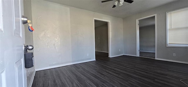 empty room with a textured ceiling, dark wood-type flooring, and ceiling fan