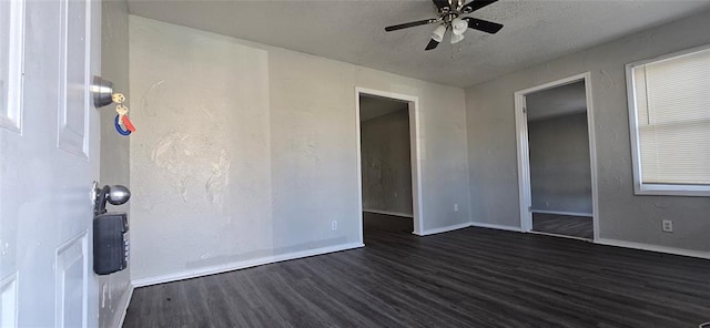 empty room with ceiling fan, dark hardwood / wood-style floors, and a textured ceiling