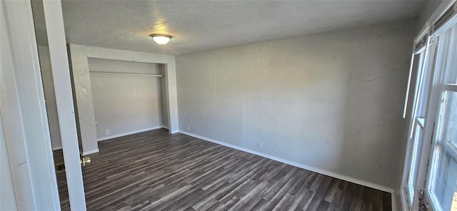 unfurnished bedroom featuring a textured ceiling, a closet, and dark hardwood / wood-style floors