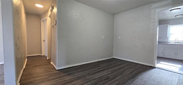 unfurnished room featuring dark wood-type flooring and sink