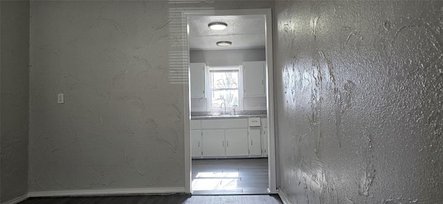 hall featuring wood-type flooring, sink, and a textured ceiling