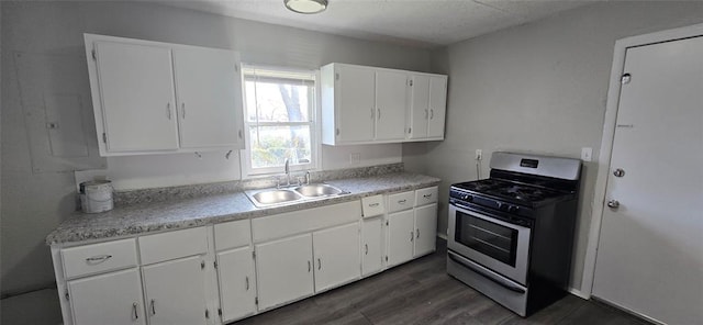 kitchen with gas range, sink, white cabinets, and dark wood-type flooring