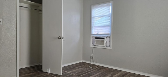 unfurnished bedroom with dark wood-type flooring, a closet, and cooling unit