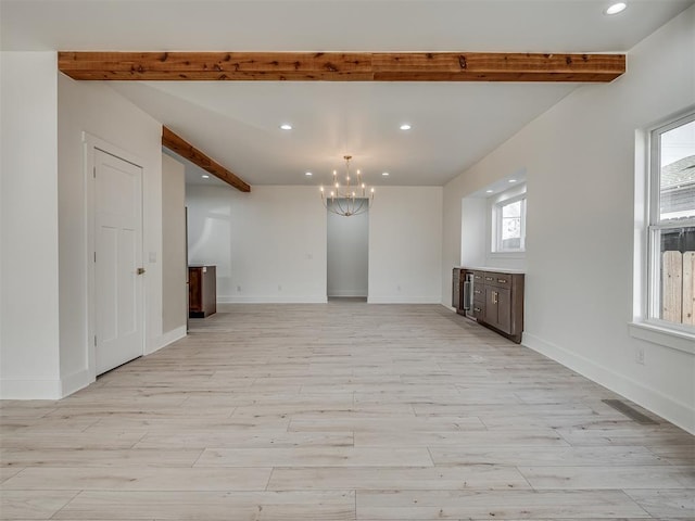 unfurnished living room with beamed ceiling, light hardwood / wood-style flooring, and a wealth of natural light