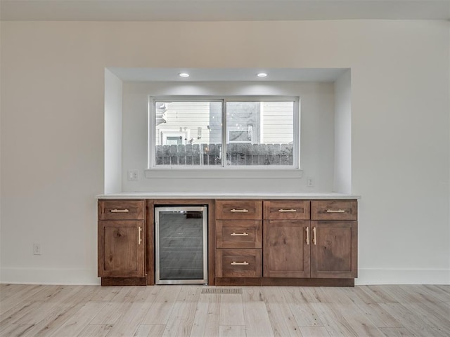 bar featuring wine cooler and light hardwood / wood-style floors