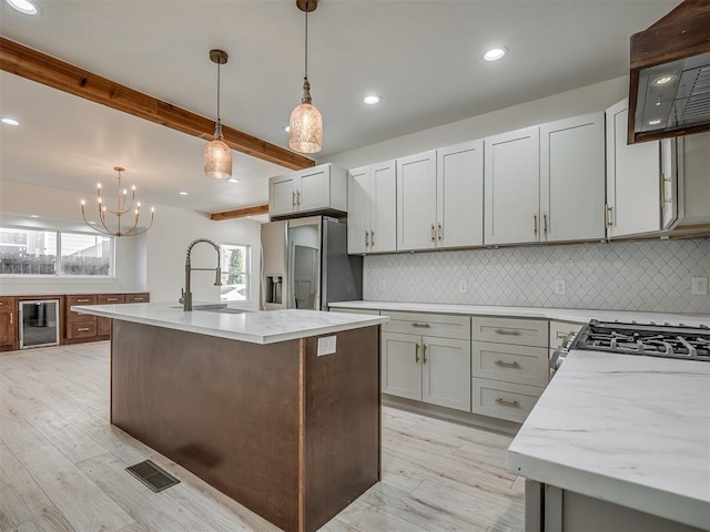 kitchen with sink, light wood-type flooring, stainless steel appliances, and an island with sink