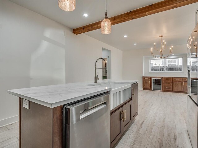 kitchen featuring stainless steel dishwasher, pendant lighting, a center island with sink, light hardwood / wood-style floors, and wine cooler