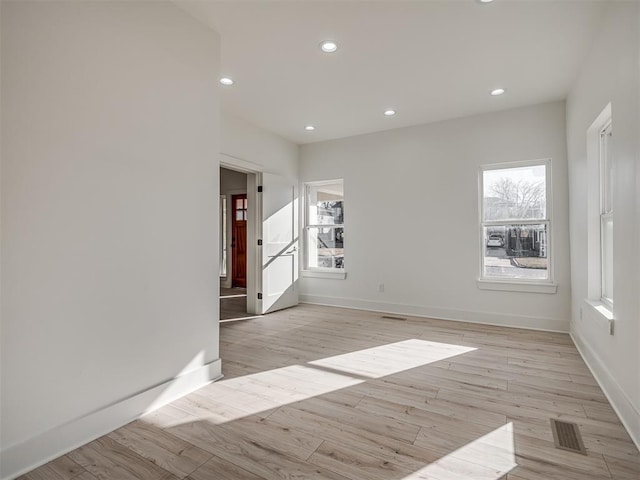 empty room with plenty of natural light and light hardwood / wood-style floors