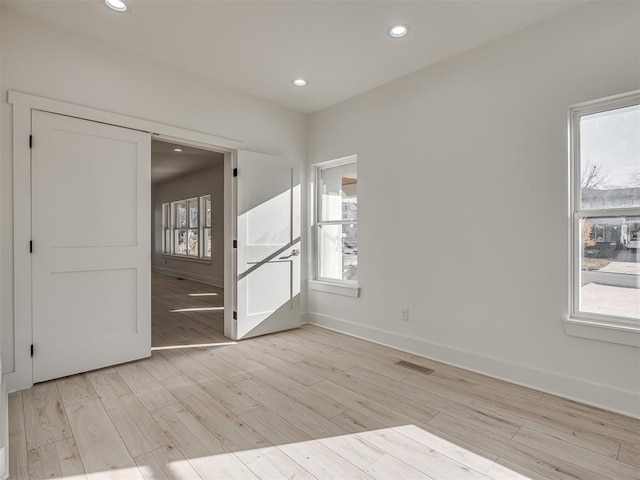 unfurnished bedroom featuring multiple windows and light hardwood / wood-style flooring