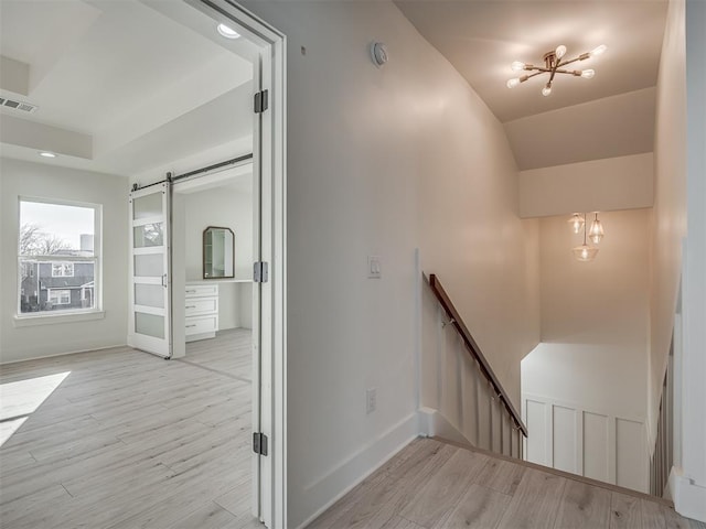 stairs with a barn door, hardwood / wood-style flooring, and a notable chandelier