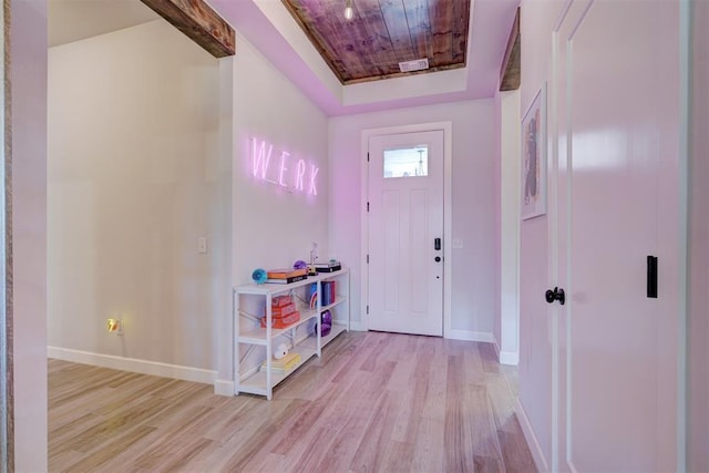 foyer entrance featuring a tray ceiling, wooden ceiling, and light wood-type flooring