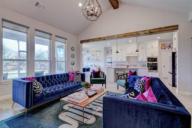 living room featuring lofted ceiling with beams, a wealth of natural light, light hardwood / wood-style floors, and a notable chandelier